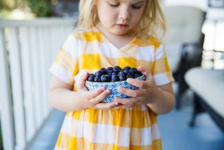 Cild holding bowl of frozen BC Blueberries. Photo credits Rhonda Dent Photography